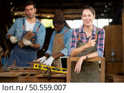 Portrait of carpenter female worker standing in front of colleague in workshop, Eyesight is utilized to ensure accuracy. Стоковое фото, агентство Ingram Publishing / Фотобанк Лори