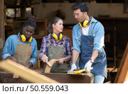 Carpenter and his assistant working together in a carpentry workshop. Стоковое фото, агентство Ingram Publishing / Фотобанк Лори