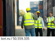 Group of workers in a container storage yard greeting each other during breaks in front of container warehouse, Стоковое фото, агентство Ingram Publishing / Фотобанк Лори