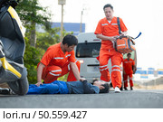 The paramedic  is assisting an injured man in an emergency situation on the road. Стоковое фото, агентство Ingram Publishing / Фотобанк Лори