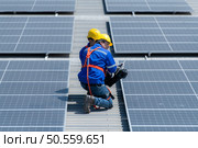 Both of technicians is installing solar panels on the roof of the warehouse to change solar energy into electrical energy for use in factories. Стоковое фото, агентство Ingram Publishing / Фотобанк Лори