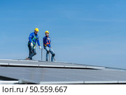 A young technician intern working on solar panels is fear of heights with senior engineers who are always helping out. Стоковое фото, агентство Ingram Publishing / Фотобанк Лори