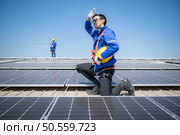 Technician repairing solar panels take off his hat and rest in the scorching sun on a factory roof covered with solar panels to receive solar energy. Стоковое фото, агентство Ingram Publishing / Фотобанк Лори