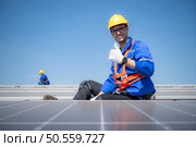 Technician repairing solar panels rest in the scorching sun on a factory roof covered with solar panels to receive solar energy. Стоковое фото, агентство Ingram Publishing / Фотобанк Лори