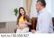 Asian pregnant woman visit gynecologist doctor at medical clinic for pregnancy consultant. Doctor examine pregnant belly for baby and mother healthcare check up. Стоковое фото, агентство Ingram Publishing / Фотобанк Лори