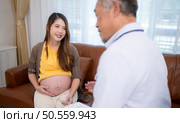 Asian pregnant woman visit gynecologist doctor at medical clinic for pregnancy consultant. Doctor examine pregnant belly for baby and mother healthcare check up. Стоковое фото, агентство Ingram Publishing / Фотобанк Лори