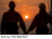 Silhouette of engineers and wind turbines at sunset, renewable energy concept, People blur of foreground. Стоковое фото, агентство Ingram Publishing / Фотобанк Лори
