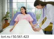 Female doctor with IV equipment will give IV fluids and examine patients lying in hospital beds. Стоковое фото, агентство Ingram Publishing / Фотобанк Лори