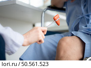 A doctor uses a reflex hammer to evaluate a patient’s knee joint. Стоковое фото, агентство Ingram Publishing / Фотобанк Лори