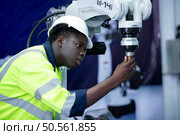 Technician who maintains a small robot arm the operation of a small robot arm used in industry is being repaired. Стоковое фото, агентство Ingram Publishing / Фотобанк Лори