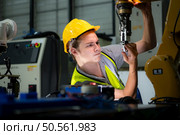 Technician who maintains a small robot arm the operation of a small robot arm used in industry is being repaired. Стоковое фото, агентство Ingram Publishing / Фотобанк Лори