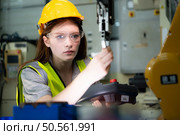 Female technician who maintains a small robot arm the operation of a small robot arm used in industry is being repaired. Стоковое фото, агентство Ingram Publishing / Фотобанк Лори
