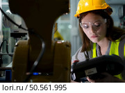 Female technician who maintains a small robot arm the operation of a small robot arm used in industry is being repaired. Стоковое фото, агентство Ingram Publishing / Фотобанк Лори