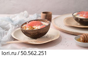 Yogurt with grapefruit, granola, chia and honey served in half a coconut shell on a rose marble kitchen countertop. Стоковое фото, агентство Ingram Publishing / Фотобанк Лори