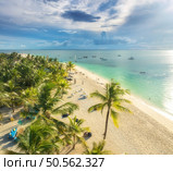 Aerial view of white sandy beach with palms, umbrellas, yachts, boats, blue ocean, sky with clouds at sunset. Summer vacation in Kendwa, Zanzibar island. Tropical landscape. Clear sea. Top view. Стоковое фото, агентство Ingram Publishing / Фотобанк Лори