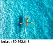 Aerial view of young woman lying on transparent canoe in blue sea at sunset. Summer in Zanzibar. Top drone view of beautiful slim girl, kanoe, ocean with clear water. Tropical background. Travel. Стоковое фото, агентство Ingram Publishing / Фотобанк Лори