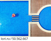 Aerial view of young woman on swimming ring in pool near ocean on summer sunny day. Top drone view of beautiful girl, blue water. Pwani Mchangani, Zanzibar. Travel background. Tropical landscape. Стоковое фото, агентство Ingram Publishing / Фотобанк Лори