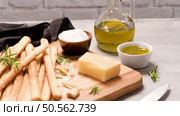 Fresh baked homemade grissini bread sticks in vintage metal grid box with olive oil and rosemary herbs over kitchen counter top. Стоковое фото, агентство Ingram Publishing / Фотобанк Лори