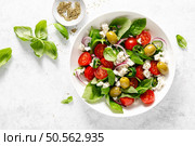 Fresh healthy vegetable Mediterranean salad of feta cheese, tomato, olives, green pepper and green basil leaves, top view. Стоковое фото, агентство Ingram Publishing / Фотобанк Лори