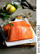 Salmon. Fresh raw salmon fish fillet with cooking ingredients, herbs and lemon on dark background. Salmon. Fresh raw salmon fish fillet with cooking ingredients, herbs and lemon on dark background. Стоковое фото, агентство Ingram Publishing / Фотобанк Лори