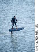 A man rides an electric hydrofoil surfboard, gliding smoothly above the water surface, enjoying a unique water sport experience. Стоковое фото, агентство Ingram Publishing / Фотобанк Лори