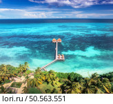Aerial view of bungalow, jetty, white sandy beach, ocean at sunset. Summer in Zanzibar.. Restaurant on the sea. Top drone view of wooden hotel, azure water, green palms, sky with clouds. Luxury resort. Стоковое фото, агентство Ingram Publishing / Фотобанк Лори