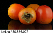 Red ripe persimmons rotating over black background. Стоковое фото, агентство Ingram Publishing / Фотобанк Лори