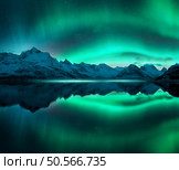 Aurora borealis over the snowy mountains, frozen sea, reflection in water at winter night. Lofoten, Norway. Northern lights and snowy rocks. Landscape with polar lights, starry sky and fjord. Scenery. Стоковое фото, агентство Ingram Publishing / Фотобанк Лори