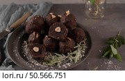 Dark chocolate truffles with hazelnuts and chopped hazelnuts over wooden cutting board. Стоковое фото, агентство Ingram Publishing / Фотобанк Лори