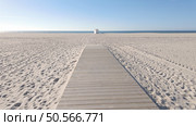 A wide wooden walkway stretches across a vast, pristine beach, leading towards a small white lifeguard tower under a clear blue sky. Стоковое фото, агентство Ingram Publishing / Фотобанк Лори