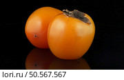 Red ripe persimmons rotating over black background. Стоковое фото, агентство Ingram Publishing / Фотобанк Лори