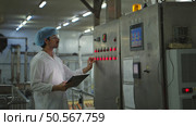 The production control supervisor inspects and controls the operation of machines in the manufacturing line of a canned fish industry. Стоковое фото, агентство Ingram Publishing / Фотобанк Лори