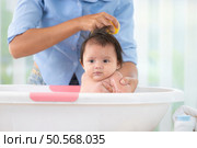 A mother bathes her little daughter in a small children’s tub. Стоковое фото, агентство Ingram Publishing / Фотобанк Лори