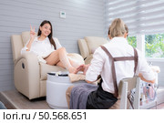 A nail technician is using tools to cut and polish foot of a customer. Стоковое фото, агентство Ingram Publishing / Фотобанк Лори