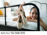 A girl ballet student look at the old ballet shoes hanging from the end of the bed, happy smile. Стоковое фото, агентство Ingram Publishing / Фотобанк Лори