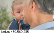 A tiny child cries while being carried and played with by grandfather. Стоковое фото, агентство Ingram Publishing / Фотобанк Лори