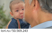 A tiny child cries while being carried and played with by grandfather. Стоковое фото, агентство Ingram Publishing / Фотобанк Лори