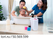 Parents bathe little child after ate meal. Стоковое фото, агентство Ingram Publishing / Фотобанк Лори