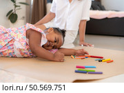 On a holiday, A woman and her little daughters sit on the floor and drawing together in the living room. Стоковое фото, агентство Ingram Publishing / Фотобанк Лори