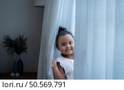 A tiny girl plays hide-and-seek with drapes in her bedroom. Стоковое фото, агентство Ingram Publishing / Фотобанк Лори