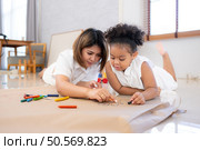 On a holiday, A woman and her little daughters sit on the floor and drawing together in the living room. Стоковое фото, агентство Ingram Publishing / Фотобанк Лори