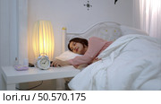 Asian young woman on the bed in the bedroom trying to wake up and prepare for work. Стоковое фото, агентство Ingram Publishing / Фотобанк Лори