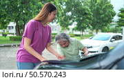 Grandmother and grandchild help each other execute a basic engine check on their parents’ automobile. Стоковое фото, агентство Ingram Publishing / Фотобанк Лори