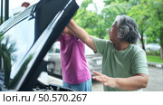 Grandmother and grandchild help each other execute a basic engine check on their parents’ automobile. Стоковое фото, агентство Ingram Publishing / Фотобанк Лори