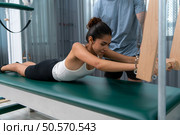 A young man and a young woman are doing pilates exercises on a pilates cadillac. Стоковое фото, агентство Ingram Publishing / Фотобанк Лори