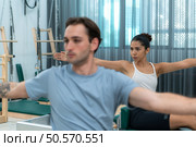 A young man and a young woman are doing pilates exercises on a pilates reformer. Стоковое фото, агентство Ingram Publishing / Фотобанк Лори