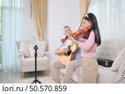 A girl violinist and her grandfather practice music together at home. Стоковое фото, агентство Ingram Publishing / Фотобанк Лори