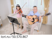 A girl violinist and her grandfather practice music together at home. Стоковое фото, агентство Ingram Publishing / Фотобанк Лори