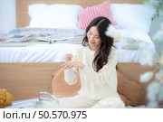 Asian young women conducting their weekly holiday routines from getting up, putting on cosmetics and relaxing. Стоковое фото, агентство Ingram Publishing / Фотобанк Лори