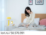 Asian woman feels unwell after waking up in the morning on a work day. Стоковое фото, агентство Ingram Publishing / Фотобанк Лори